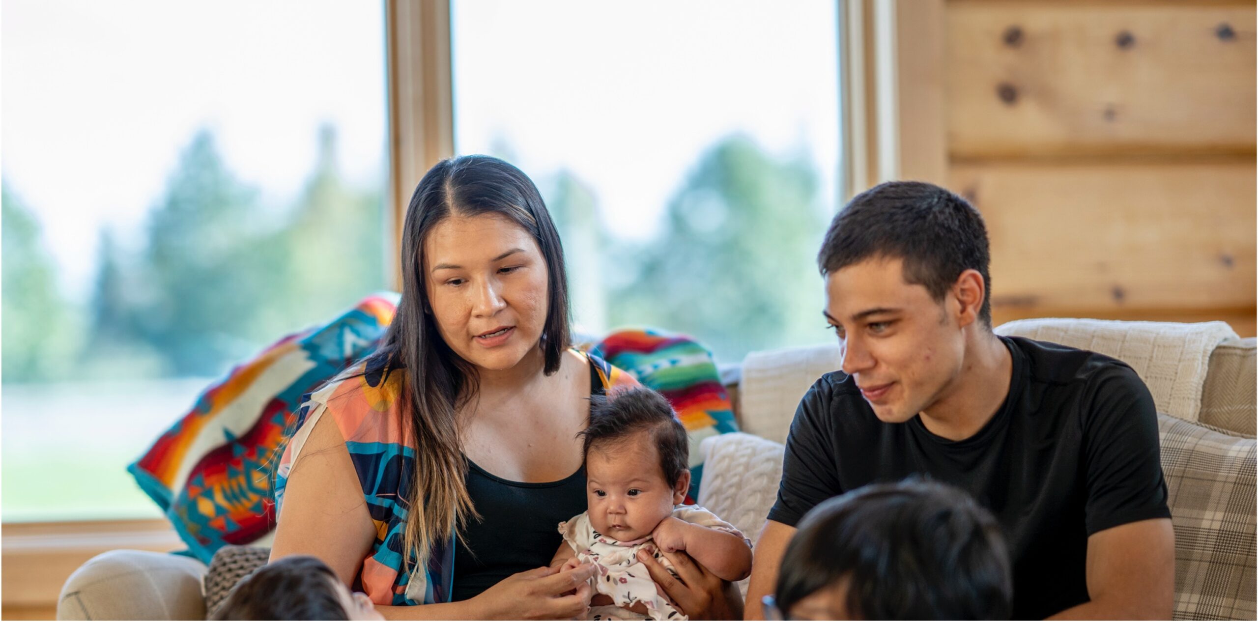 indigenous mom and dad and baby sitting on couch
